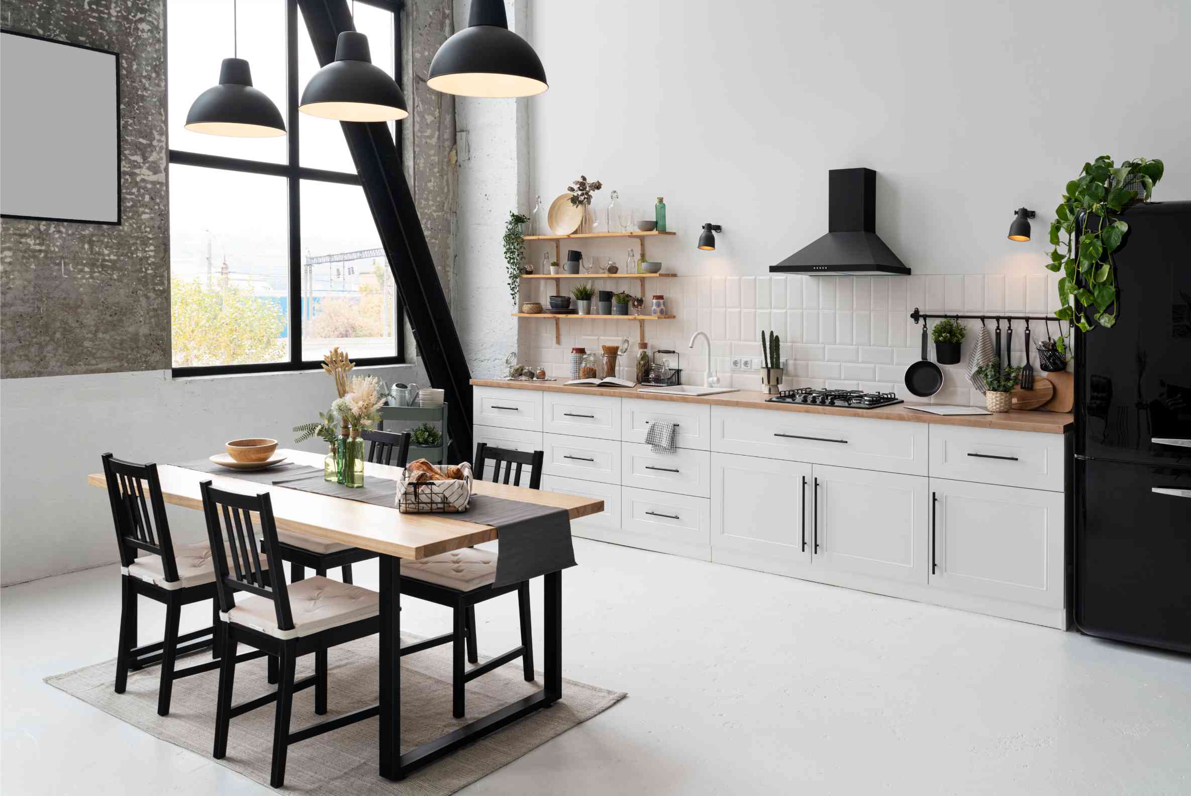 White shaker kitchen with butcher-block counters, black range hood and matching dining table