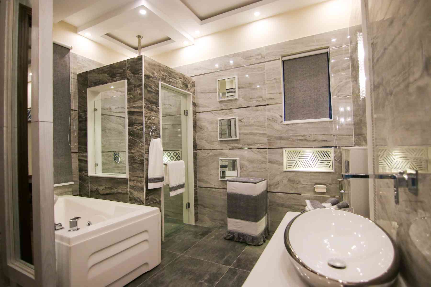 Marble-tiled bathroom with a corner glass shower, jetted tub, vessel sink and recessed wall niches
